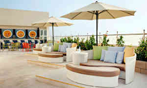 En terrasse med moderne siddegrupper, parasoller og en udsmykket bar i baggrunden. (AI-genereret tekst)