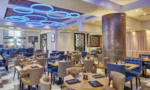 En restaurant med borde og stole, moderne indretning og dekorativ belysning. (AI-genereret tekst)