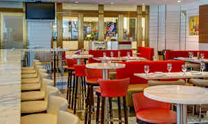 Et moderne restaurantinteriør med borde, stole og en bar med høje stole. (AI-genereret tekst)