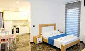 Et soveværelse med en dobbeltseng, bord med stole og en lille køkkenafdeling. (AI-genereret tekst)