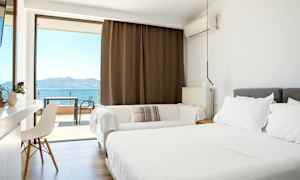 Lyst hotelværelse med dobbeltseng og balkon med havudsigt. (AI-genereret tekst)