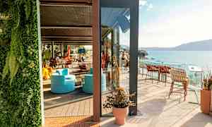 En solrig terrasse med siddepladser og havudsigt. (AI-genereret tekst)