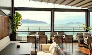 Udendørsområde med siddepladser med udsigt over havet og øer. (AI-genereret tekst)