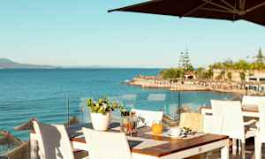 Udsigt over havet fra en restaurantterrasse med hvide borde og stole. (AI-genereret tekst)