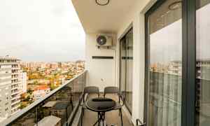 En altan med et bord og stole, med udsigt over en by. (AI-genereret tekst)