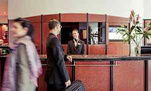 Reception i en hotellobby med en gæst og en receptionsmedarbejder. (AI-genereret tekst)