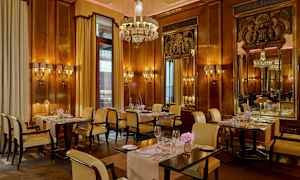 Restaurant med elegant interiør, træpaneler på væggene, lysekrone og dækkede borde. (AI-genereret tekst)