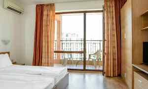 Et hotelværelse med en seng og en altan med stole. (AI-genereret tekst)