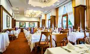 Interiør af en restaurant med dækkede borde og stole, lyse gardiner og dekorative loftlamper. (AI-genereret tekst)