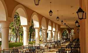 En udendørs servering med hvælvede søjler og siddegrupper. (AI-genereret tekst)