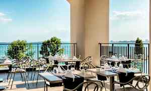 En terrasse med dækkede borde og udsigt over havet. (AI-genereret tekst)