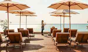 Liggestole og parasoller på en træplatform ved havet. (AI-genereret tekst)