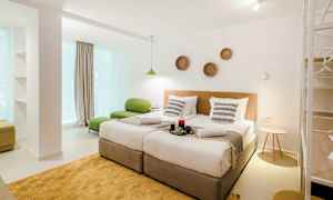 Et moderne hotelværelse med to enkeltsenge, grønt sidemøbel og dekorationer på væggen. (AI-genereret tekst)