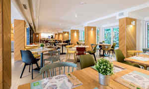 Billede af en restaurant med borde, stole og dekorationer. (AI-genereret tekst)