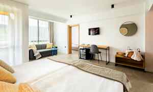 Moderne hotelværelse med dobbeltseng, sofa og skrivebord. (AI-genereret tekst)