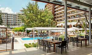 Udendørsområde ved hotel med en pool og siddepladser under tag. (AI-genereret tekst)