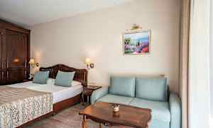 Værelse med dobbeltseng, sofa, træbord og vægdekoration. (AI-genereret tekst)