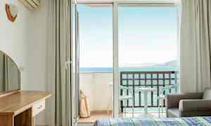 Hotelværelse med åben balkon dør og havudsigt. (AI-genereret tekst)