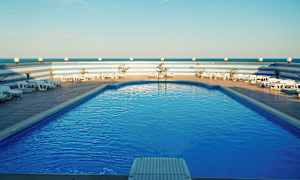 Pool med liggestole og blå himmel. (AI-genereret tekst)