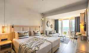 Hotelværelse med dobbeltseng, siddeområde og altan med udsigt over havet. (AI-genereret tekst)