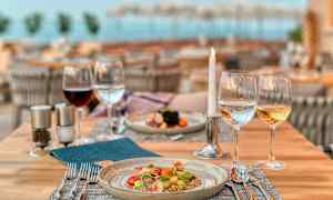 Et dækket restaurantbord med en tallerken mad og glas med vin, vand og et tændt lys. (AI-genereret tekst)