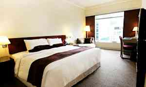 Hotelværelse med en stor seng, et skrivebord og en lænestol ved siden af et stort vindue. (AI-genereret tekst)