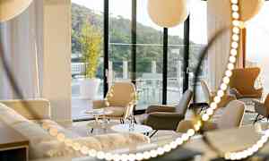 Et moderne rum med siddepladser og sofaer, store vinduer der vender ud mod en terrasse. (AI-genereret tekst)