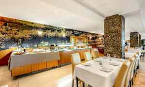 En restaurantinteriør med dækkede borde og en buffet opstillet i baggrunden. (AI-genereret tekst)