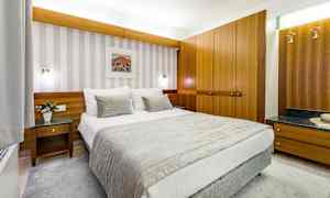 Et hotelværelse med en redt seng, træindretning og vægkunst. (AI-genereret tekst)