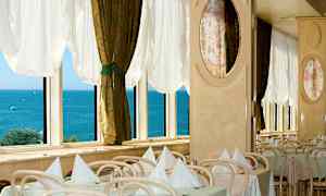 Restaurant med dækkede borde ved vinduer med udsigt over havet. (AI-genereret tekst)