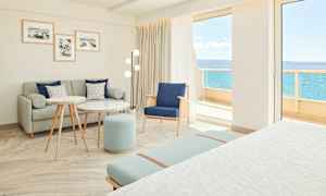 Lyst og moderne hotelværelse med siddeområde og udsigt til havet. (AI-genereret tekst)