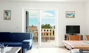 Stue med blå sofa og spisebord ved siden af en balkon med havudsigt. (AI-genereret tekst)