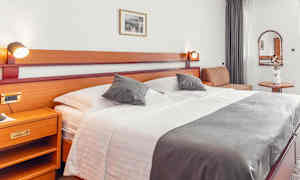 Hotelværelse med stor seng, sidebord og dekorationer. (AI-genereret tekst)