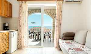 En stue med en sovesofa, et køkken og en balkon med havudsigt. (AI-genereret tekst)