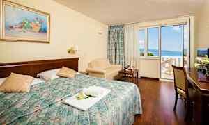 Hotelværelse med dobbeltseng og altan med havudsigt. (AI-genereret tekst)