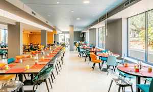 En spisesal med farverige stole og borde dækket til servering. (AI-genereret tekst)