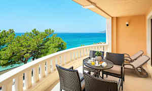 En balkon med udsigt over havet, siddegruppe og to liggestole. (AI-genereret tekst)