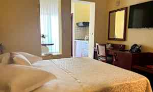 Foto af et hotelværelse med en dobbeltseng, skrivebord og et tekøkken. (AI-genereret tekst)