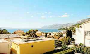 Udsigt over hustage med havet og bjerge i baggrunden. (AI-genereret tekst)