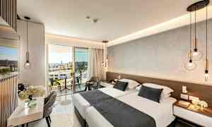 Moderne indrettet hotelværelse med dobbeltseng, siddepladser og en altan med udsigt. (AI-genereret tekst)