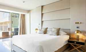 Moderne hotelværelse med stor seng, elegant indretning og udsigt til en terrasse. (AI-genereret tekst)