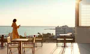 Person på en terrasse med udsigt over havet. (AI-genereret tekst)