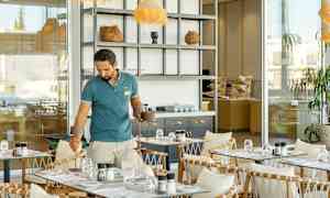 Et caféområde med borde, stole og et åbent serveringsområde. (AI-genereret tekst)