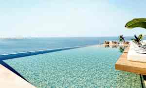 En infinitypool med udsigt over havet og solsenge omkring. (AI-genereret tekst)