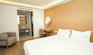 Et hotelværelse med en dobbeltseng, et skrivebord og en lænestol. I baggrunden ses et badeværelse. (AI-genereret tekst)