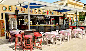 En udendørs servering med borde, stole og en bar. (AI-genereret tekst)