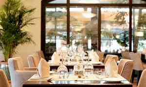 Et restaurantbord med elegant borddækning, herunder glas, tallerkener og foldede servietter. (AI-genereret tekst)