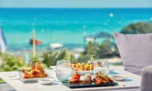 Et bord ved havet med sushi og andre asiatisk-inspirerede retter. (AI-genereret tekst)