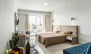 Et hotelværelse med dobbeltseng, siddeområde og en terrasse udenfor. (AI-genereret tekst)