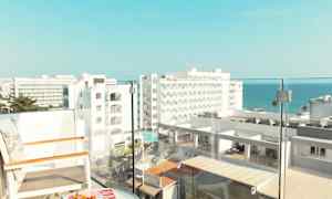 Udsigt fra en altan med stole og et bord, med hotelbygninger og havet i baggrunden. (AI-genereret tekst)